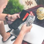 Young man looking down taking money out of his wallet to pay for something