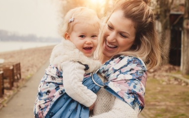A young mother holding a baby. They are both similing.