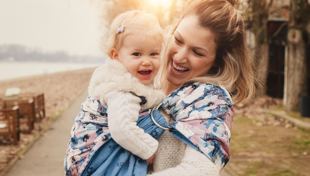 A young mother holding a baby. They are both similing.