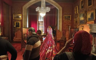 A young person taking a photo on their phone of a red dress.