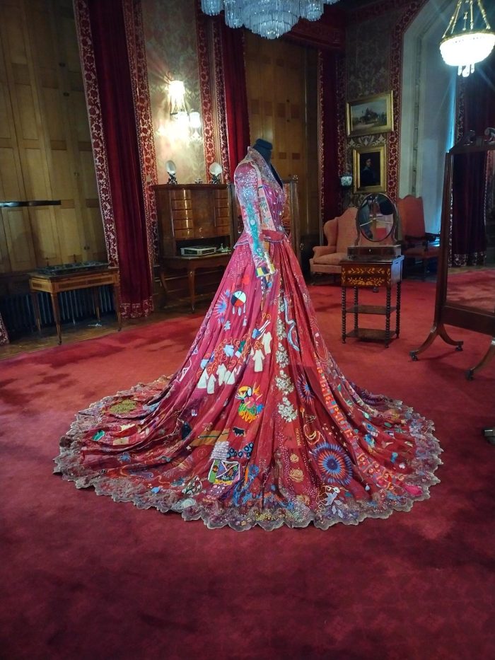 A museum display of a red dress on a mannequin.