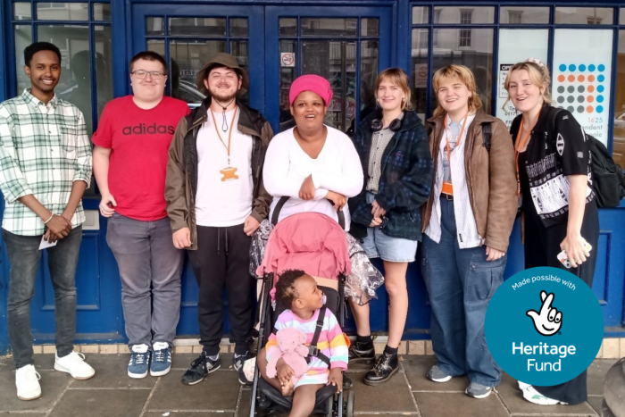 Members of the Heritage Youth Board, including a baby in a pram, standing outside Kingsley Hall, a building with dark blue doors.