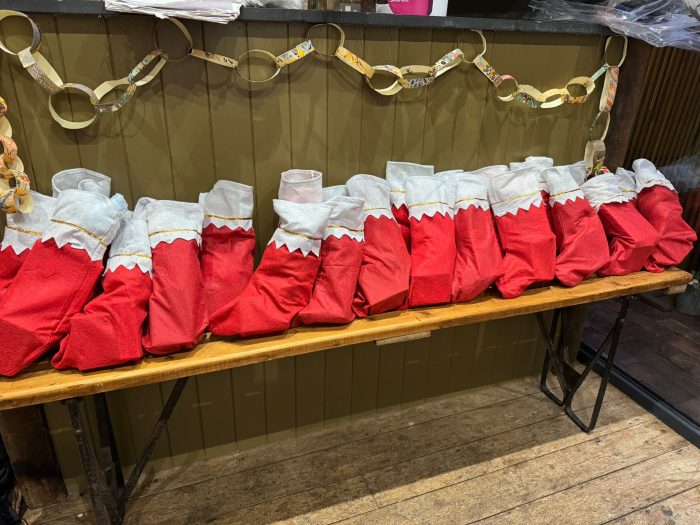 Several red Christmas stockings lined up on a wooden bench.